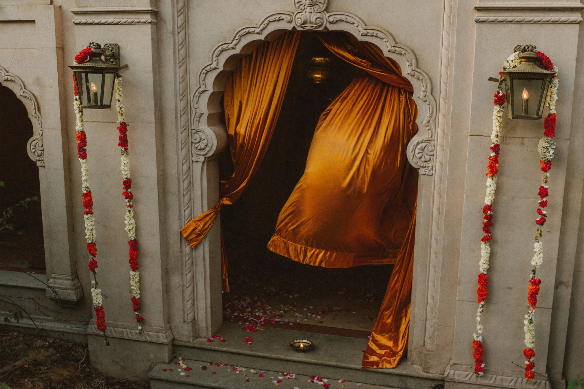 Marigold-draped stone archway entrance at an Indian wedding venue.